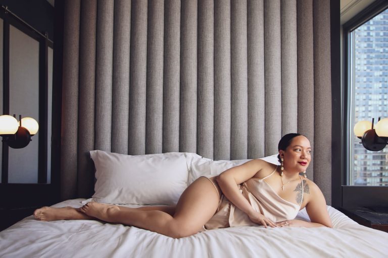 boudoir client laying on bed with pink pajama set